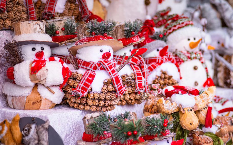 Five Snowman figures at Christmas market sitting in a row on a decorated stand.